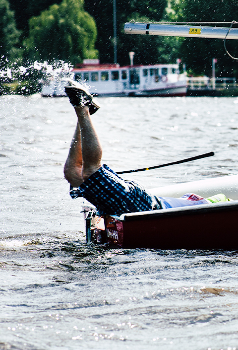 Ein Segler spritzt Wasser mit seinen Beinen. Bild einer Segelregatta.