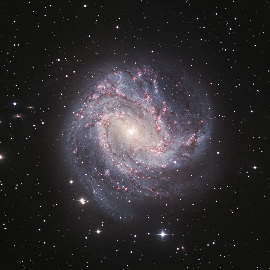 Die farbige Abbildung zeigt eine spiralförmige, hellblaue und weiße Galaxie mit einem hell leuchtendem Zentrum. Im Hintergrund ist das schwarze Universum.