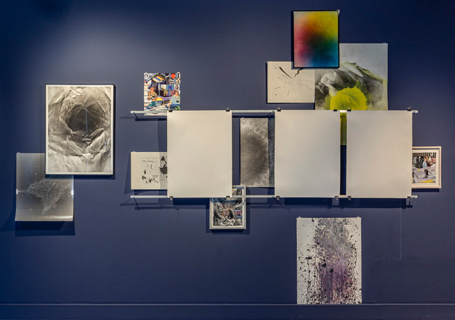 The photo shows a collage of abstract images in front of a dark blue wall. Some images are colored, others are black and white.