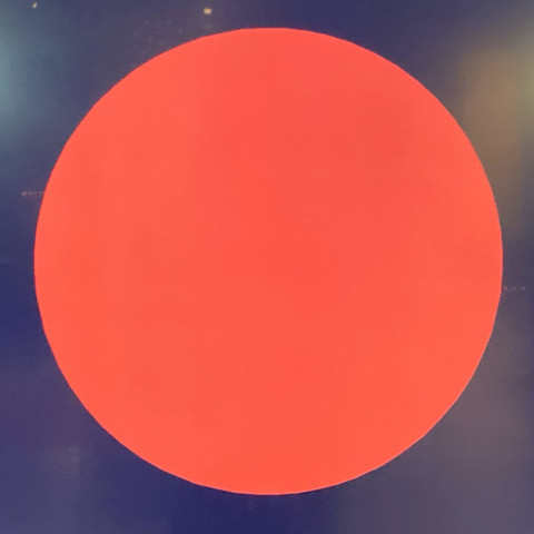 The square image shows a large red circle against a dark background.